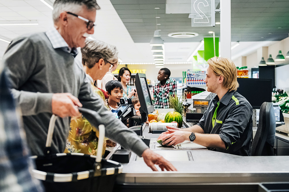 Personer som betalar för sin mat i ett kassasystem i en matvarubutik.